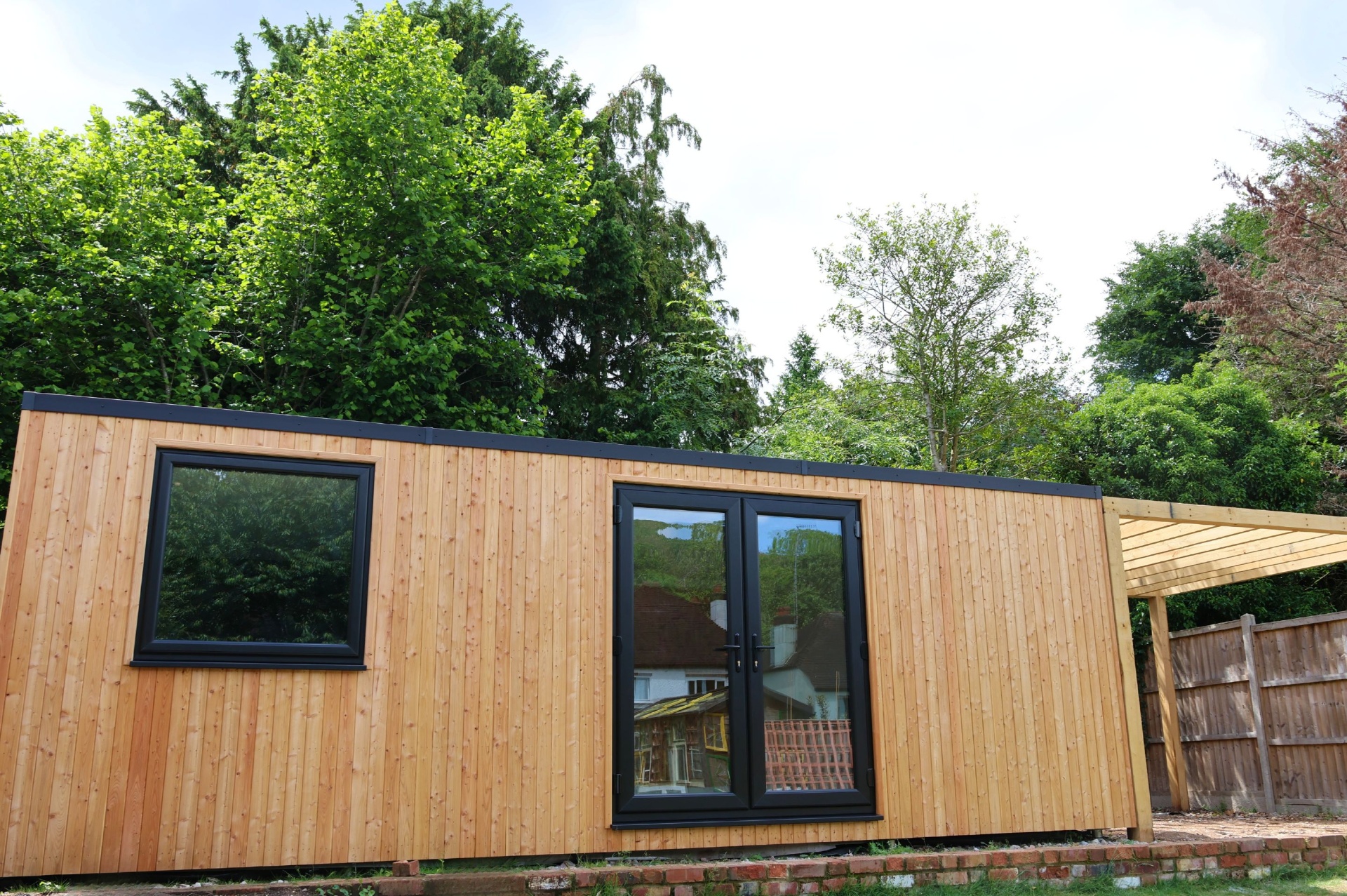 Coulsdon garden room exterior - Siberian larch clad with bifold doors and sweet chestnut pergola alongside