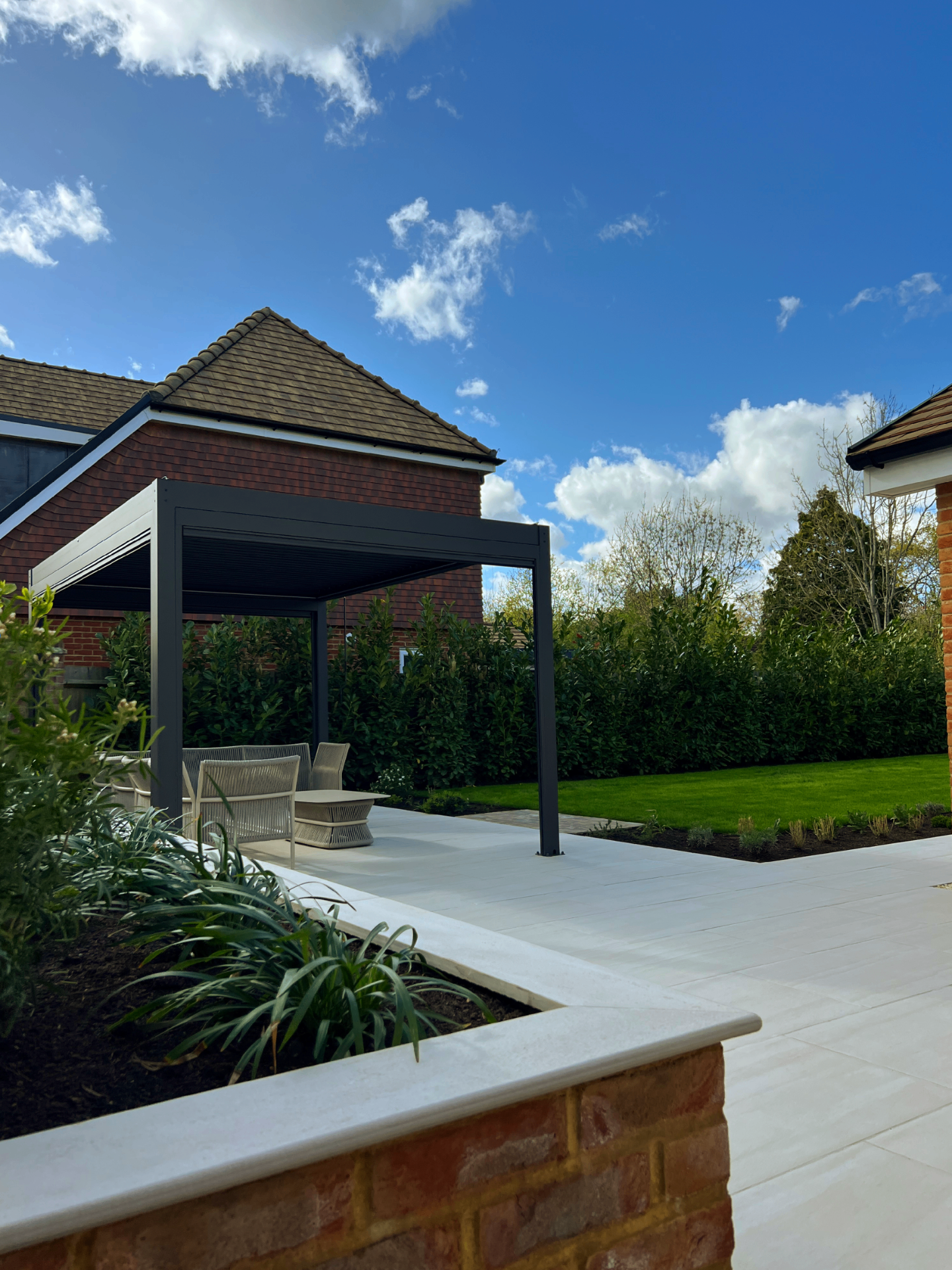 Charcoal pergola from the patio with planting and lawn beyond