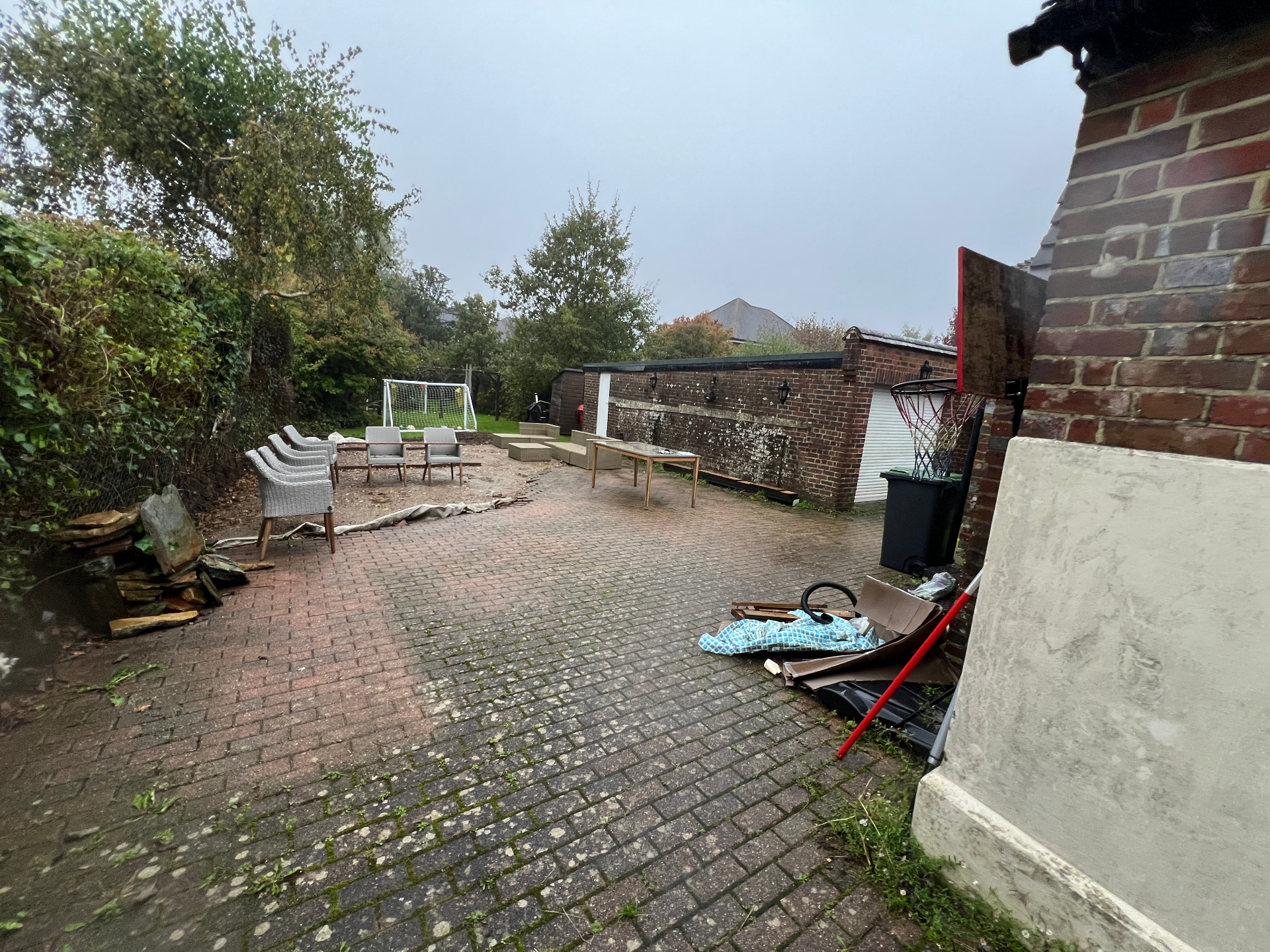 Original garden — wide view of tired block paving, mixed seating and unloved boundary walls