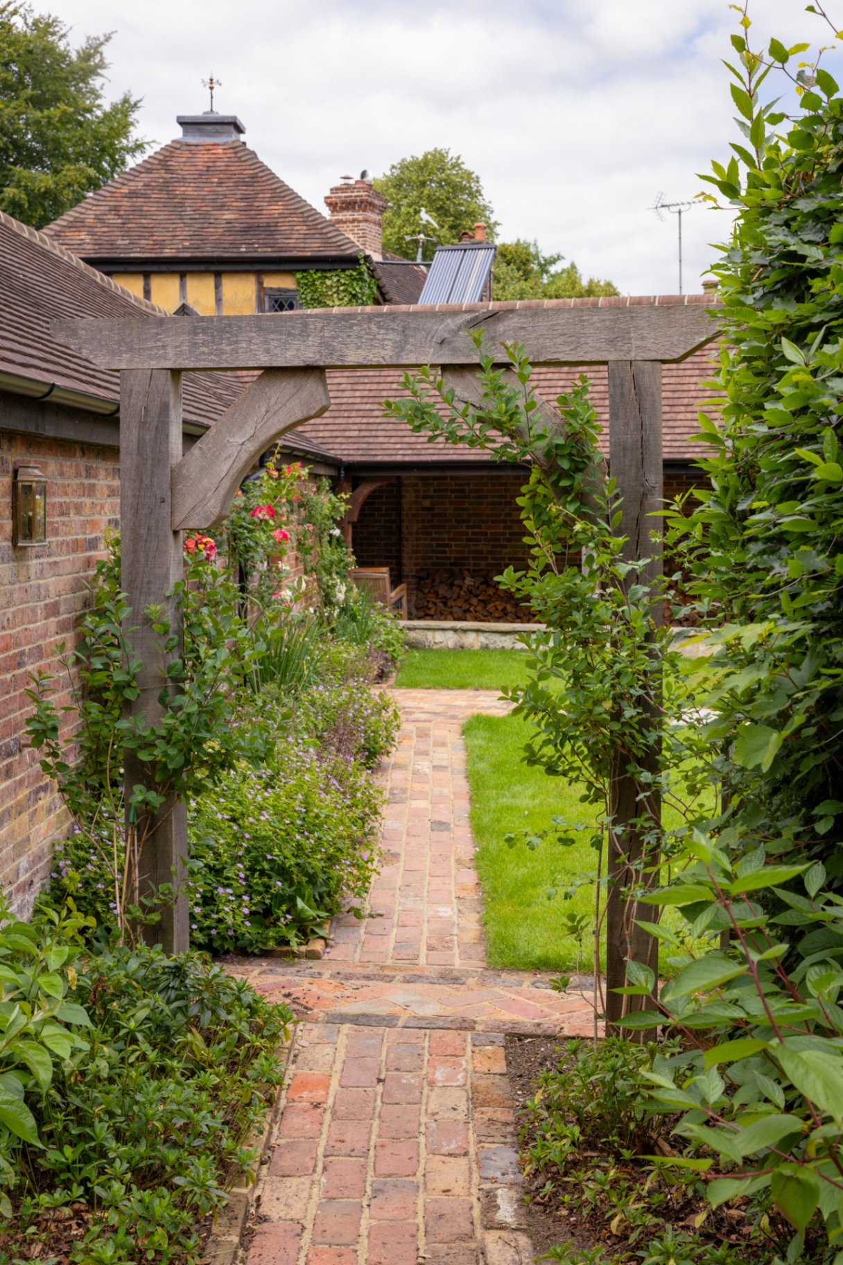 Oak pergola framing a brick path through the walled garden
