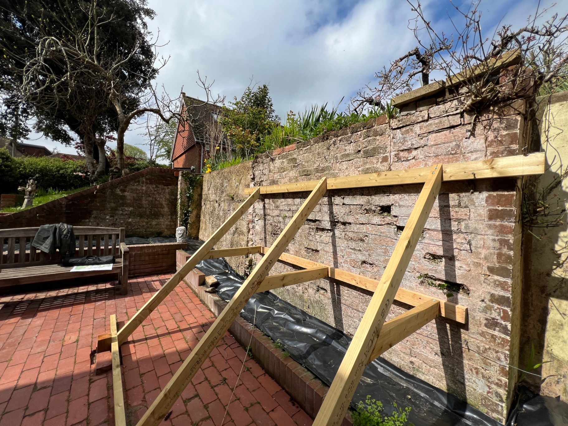 Original courtyard — crumbling brick wall with temporary timber bracing before restoration