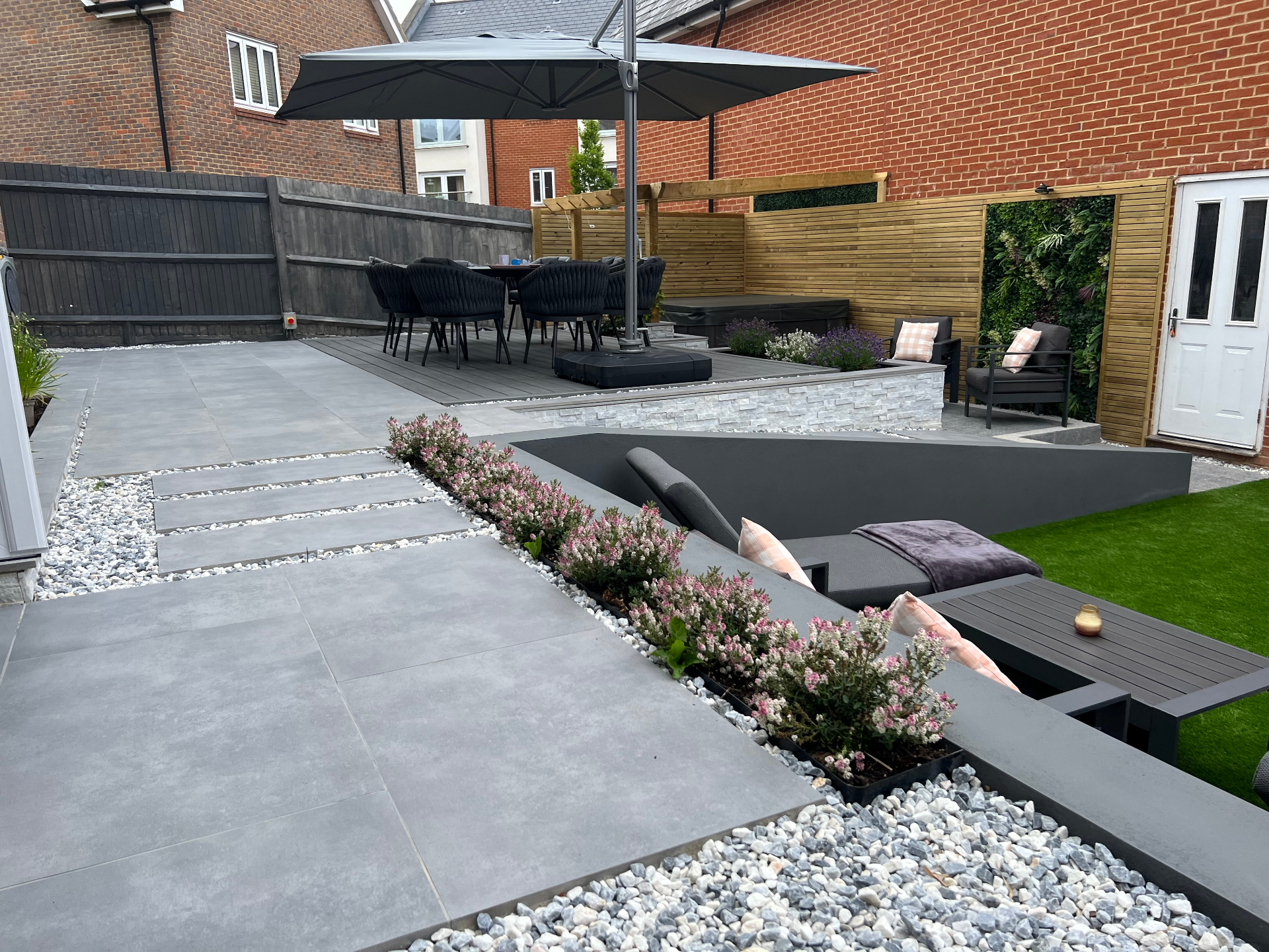 Finished garden — porcelain walkway leading to a sunken lounge, dining deck and richly planted borders
