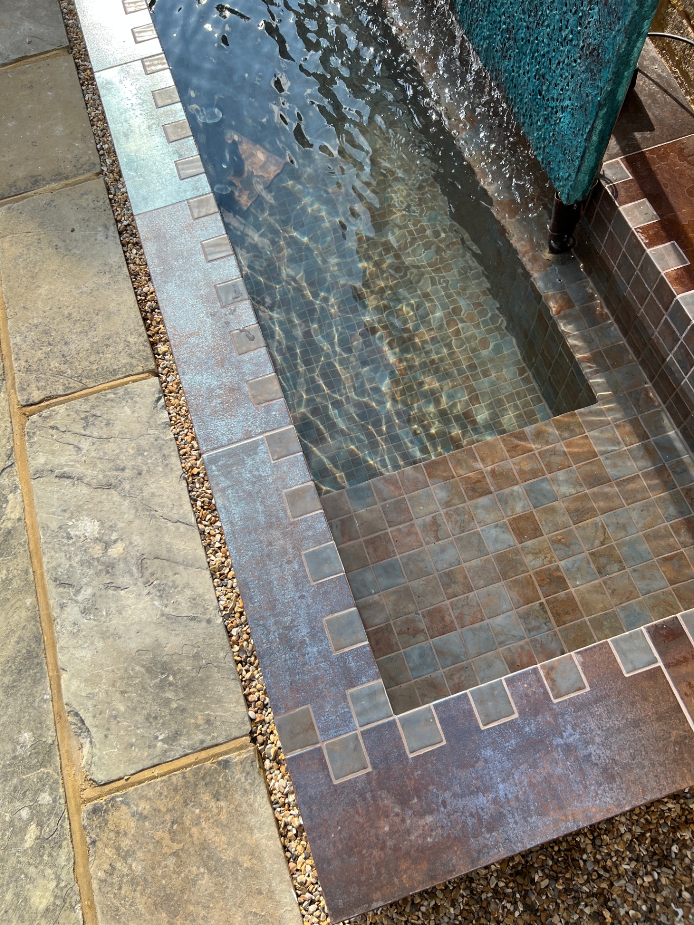Overhead view of the copper-edged rill with mosaic tiles and gravel surround