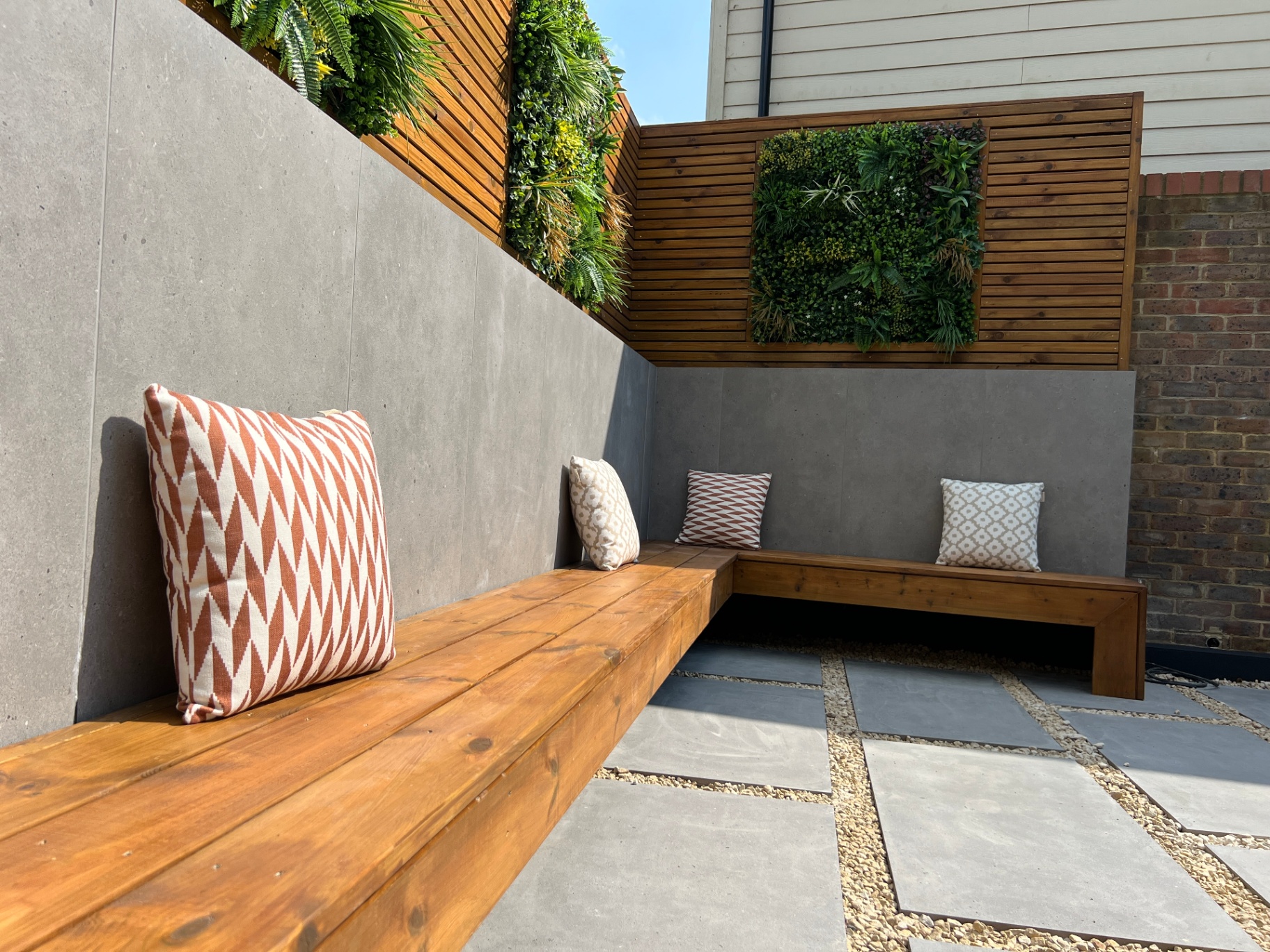 Low angle across timber bench seating and porcelain slab paving with gravel joints