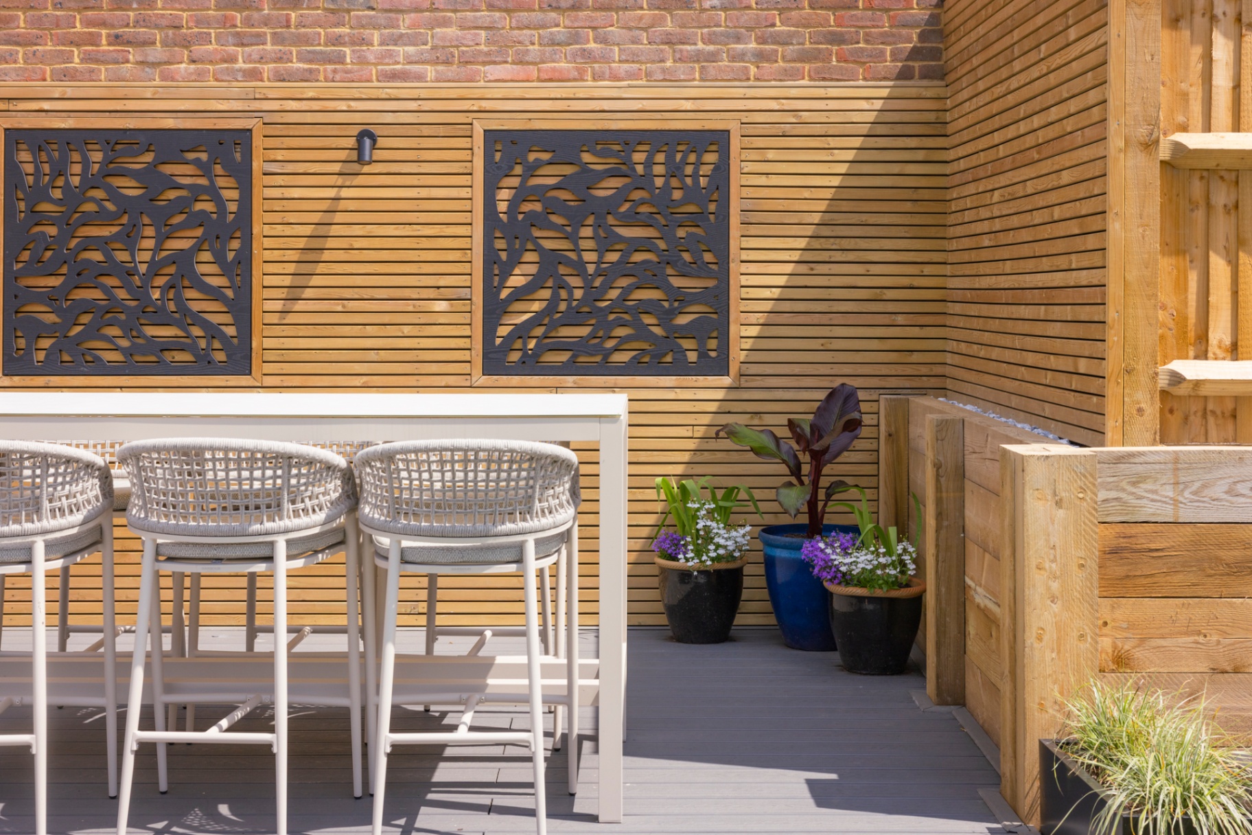 Close-up of cedar slat wall with laser-cut leaf screens and bar stools