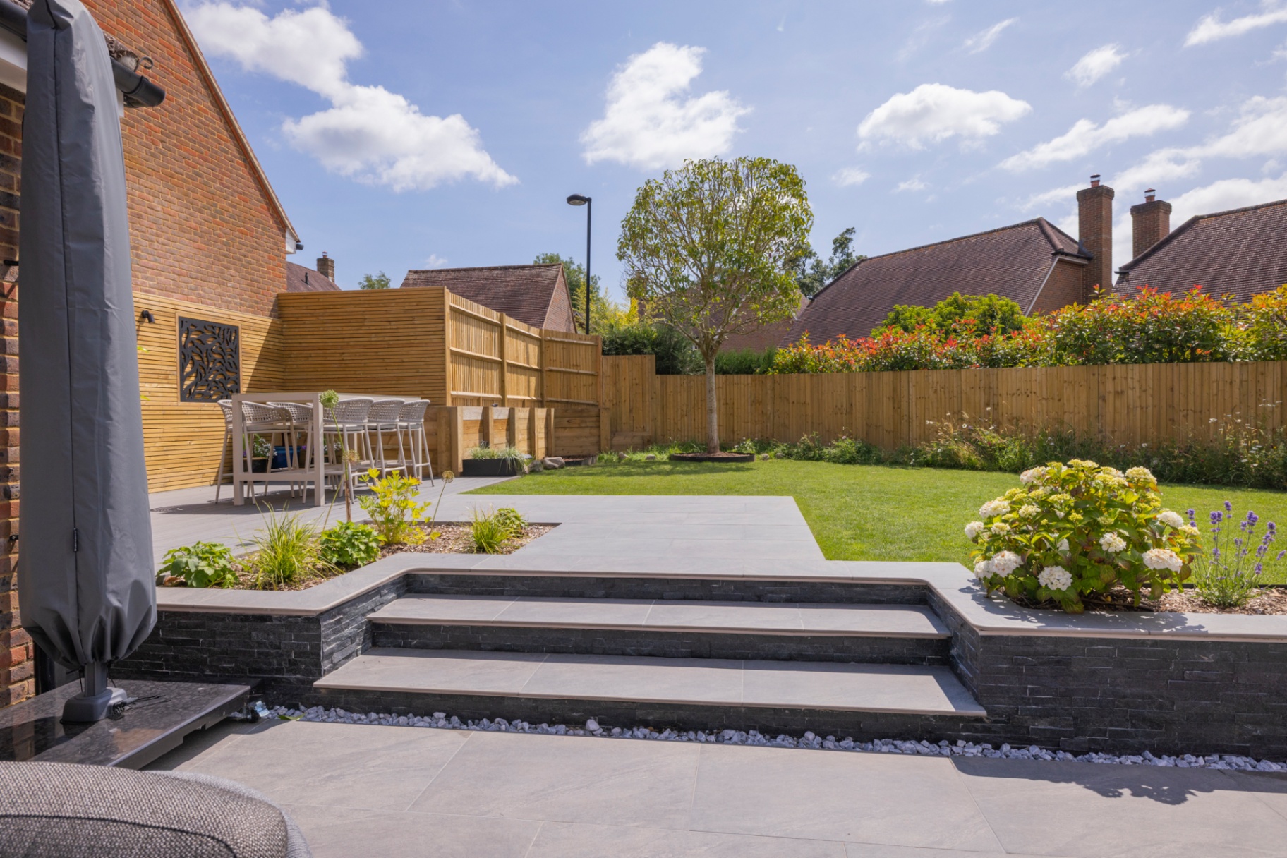 Stepped porcelain terrace leading down to the lawn and feature tree