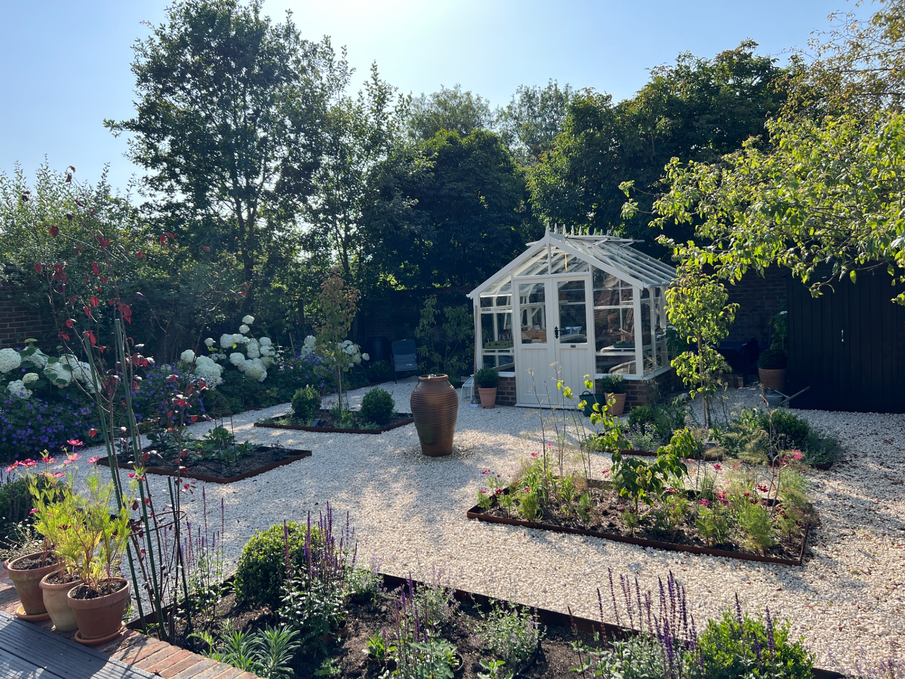 Walled flower garden — central terracotta urn with hydrangeas and cottage-style planting