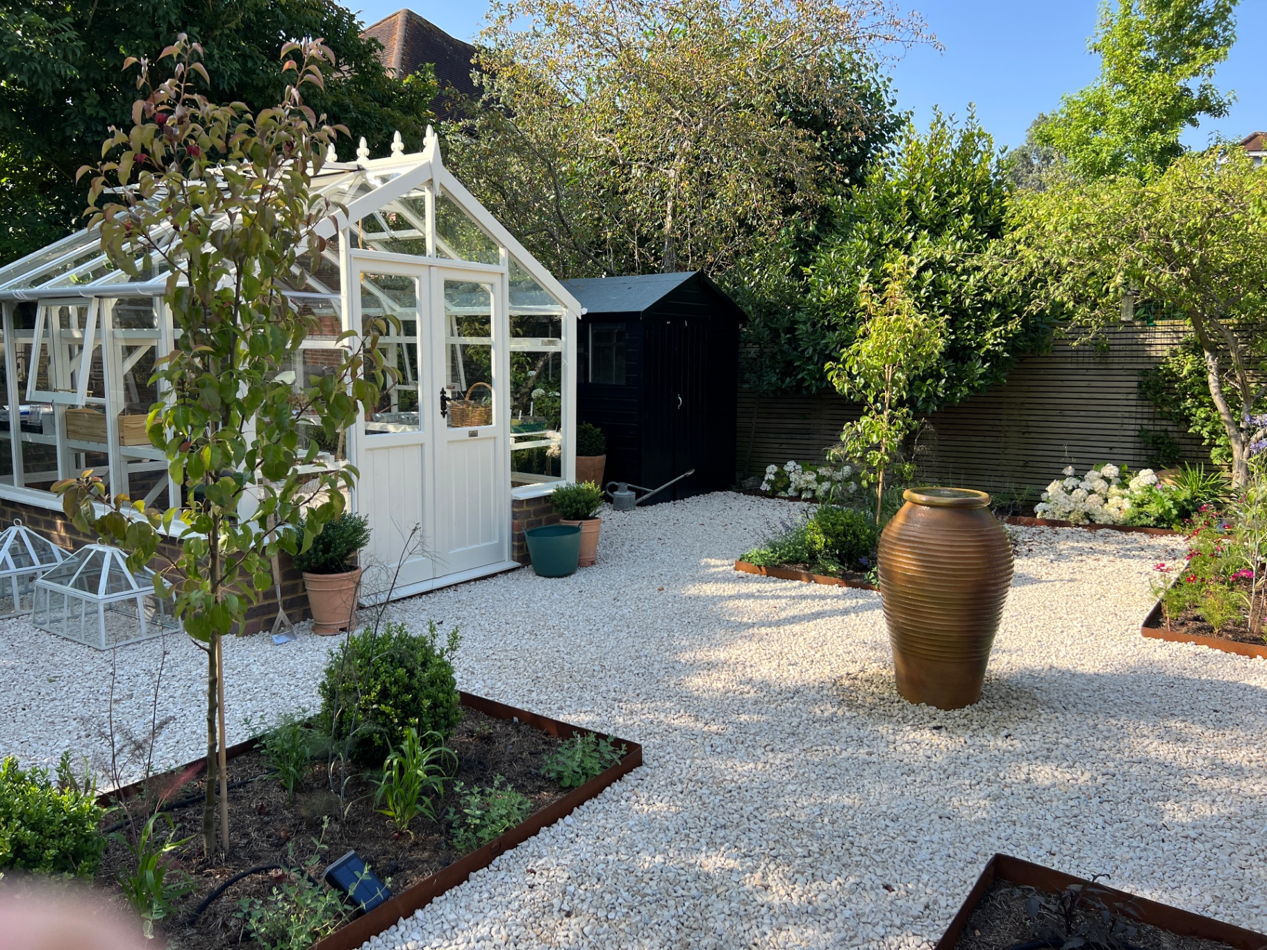 Walled flower garden — side view of the glasshouse, black shed and gravel paths
